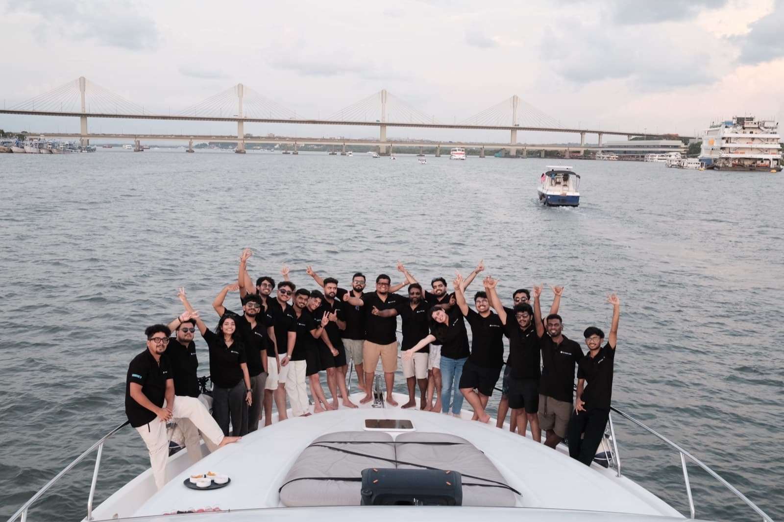 The whole Outbox Labs team on the bow of the boat with their arms up, the bridge and the water behind them