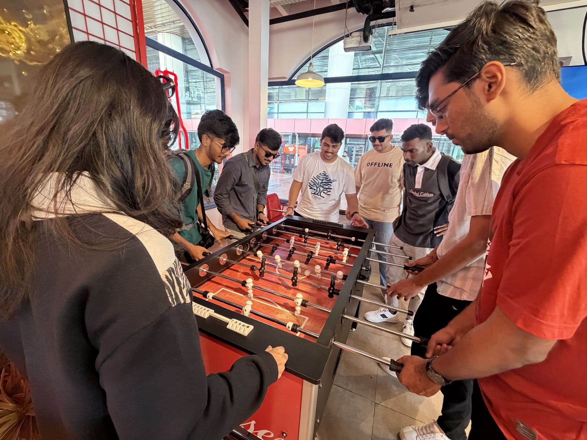 Eight people crowded around a foosball table in the office